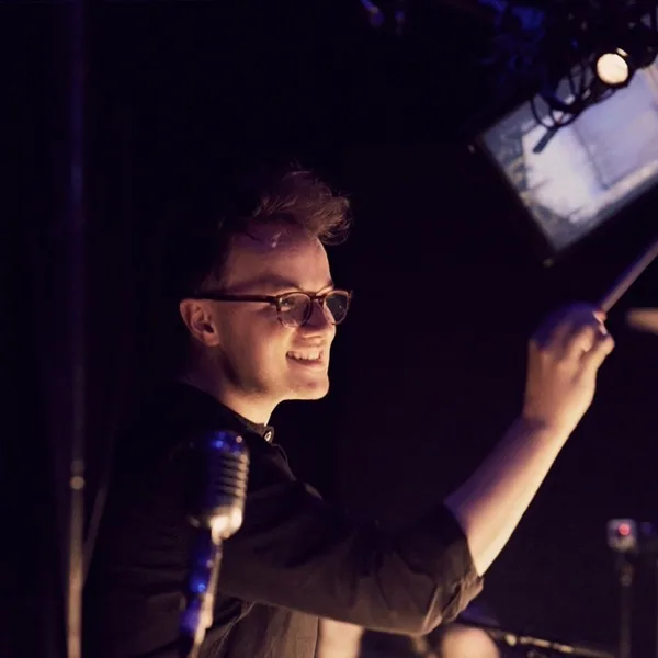 Luke Holman conducting Crazy For You in Chichester, smiling, baton raised