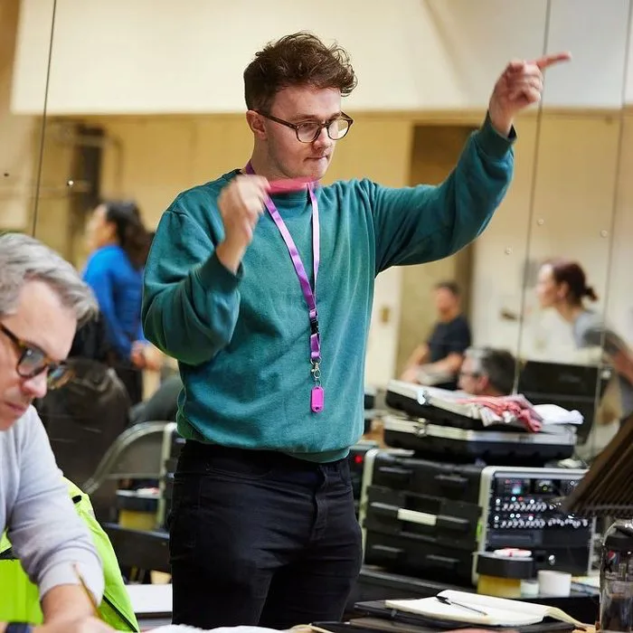 Luke Holman in rehearsal, pointing a cue across the room
