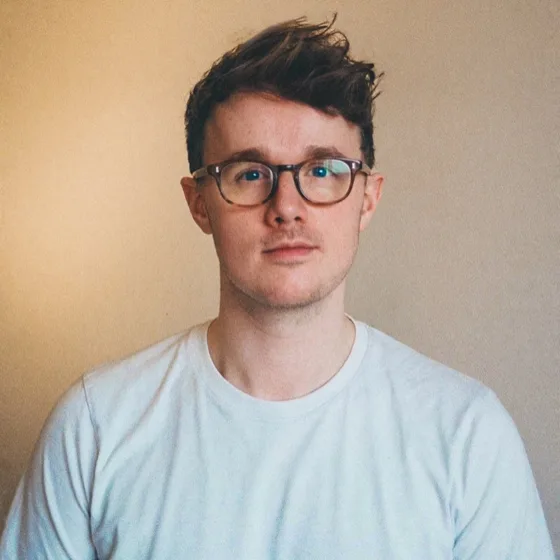 Luke Holman, photographed on film against a sand-coloured wall